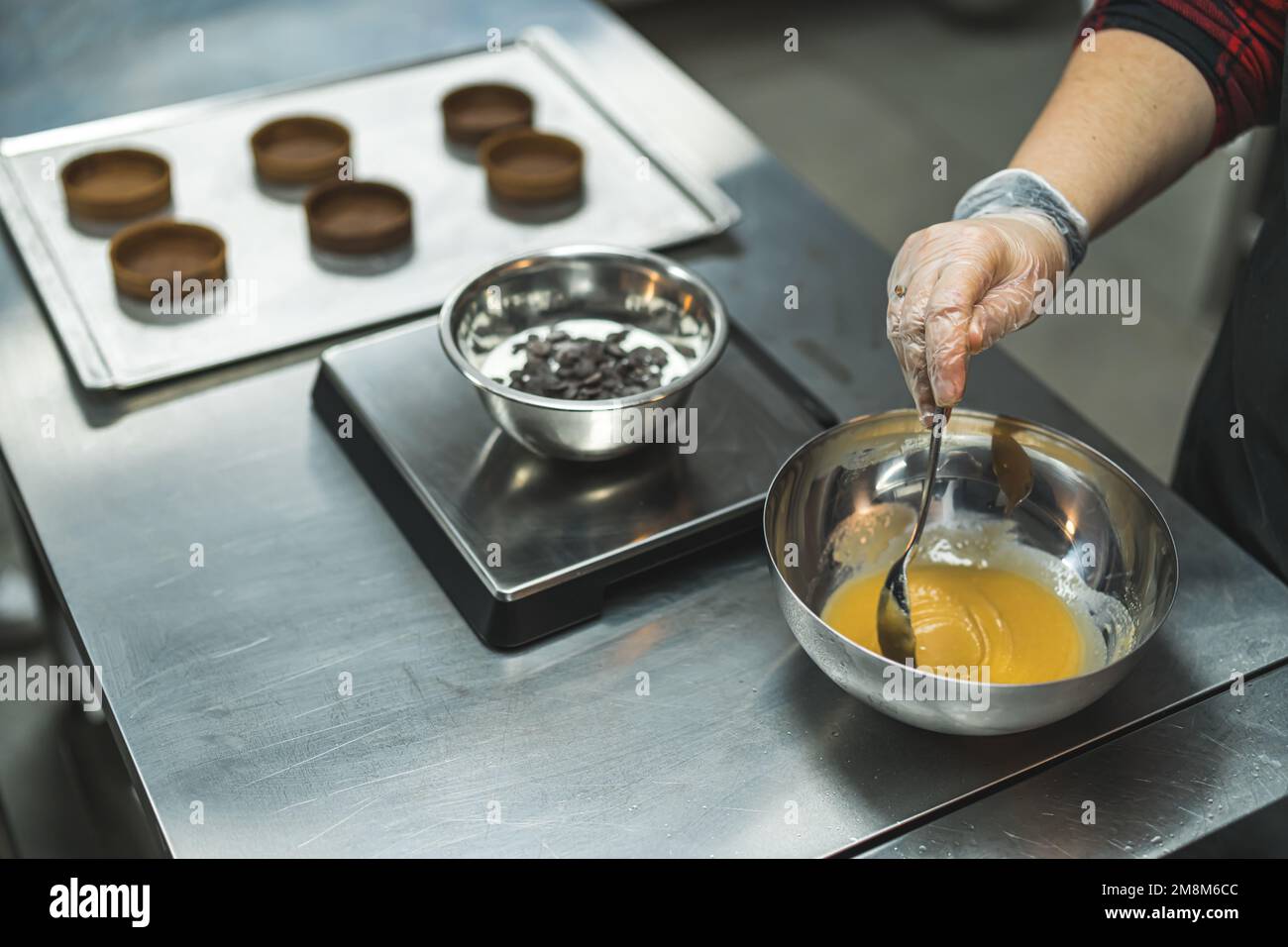 chef pouring caramel in a bowl, circle shapes on a tray in the background, bakery. High quality photo Stock Photo