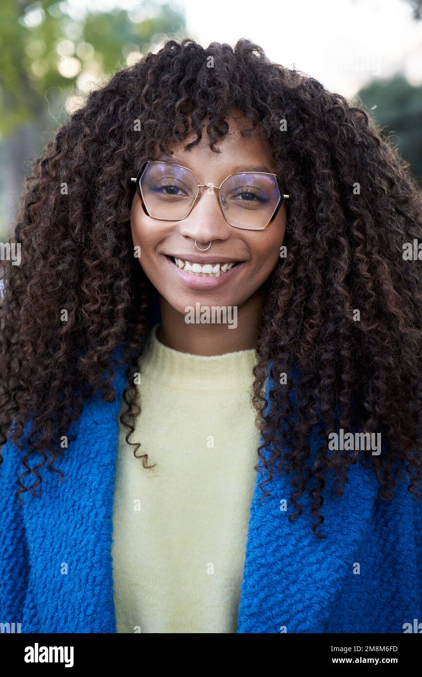 Vertical Portrait of smiling young African woman with curly hair looking camera positive expression Stock Photo