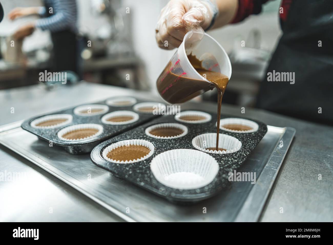 chef putting the dough into the paper cups to bake chocolate muffins, bakery concept. High quality photo Stock Photo