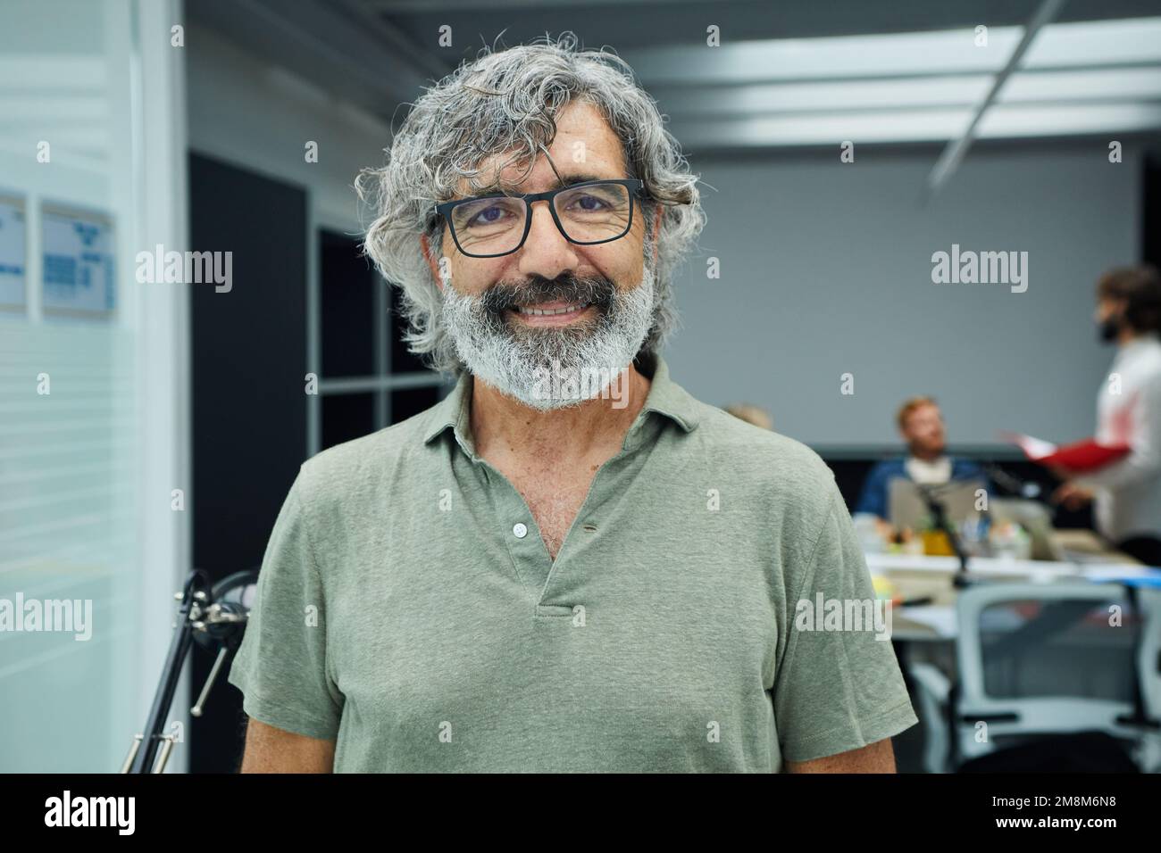 Smiling mature businessman looking camera standing in office at team board meeting Stock Photo