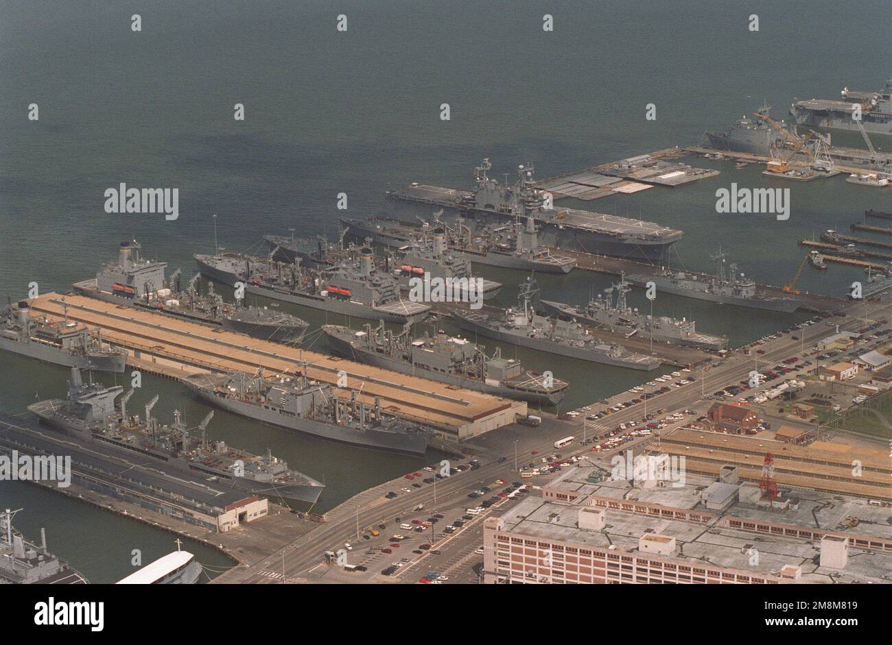 An aerial view of a section of the Norfolk Naval Base with the Defense  Supply Facility in the lower right corner. Tied up at piers #3 through #6  is a vast array