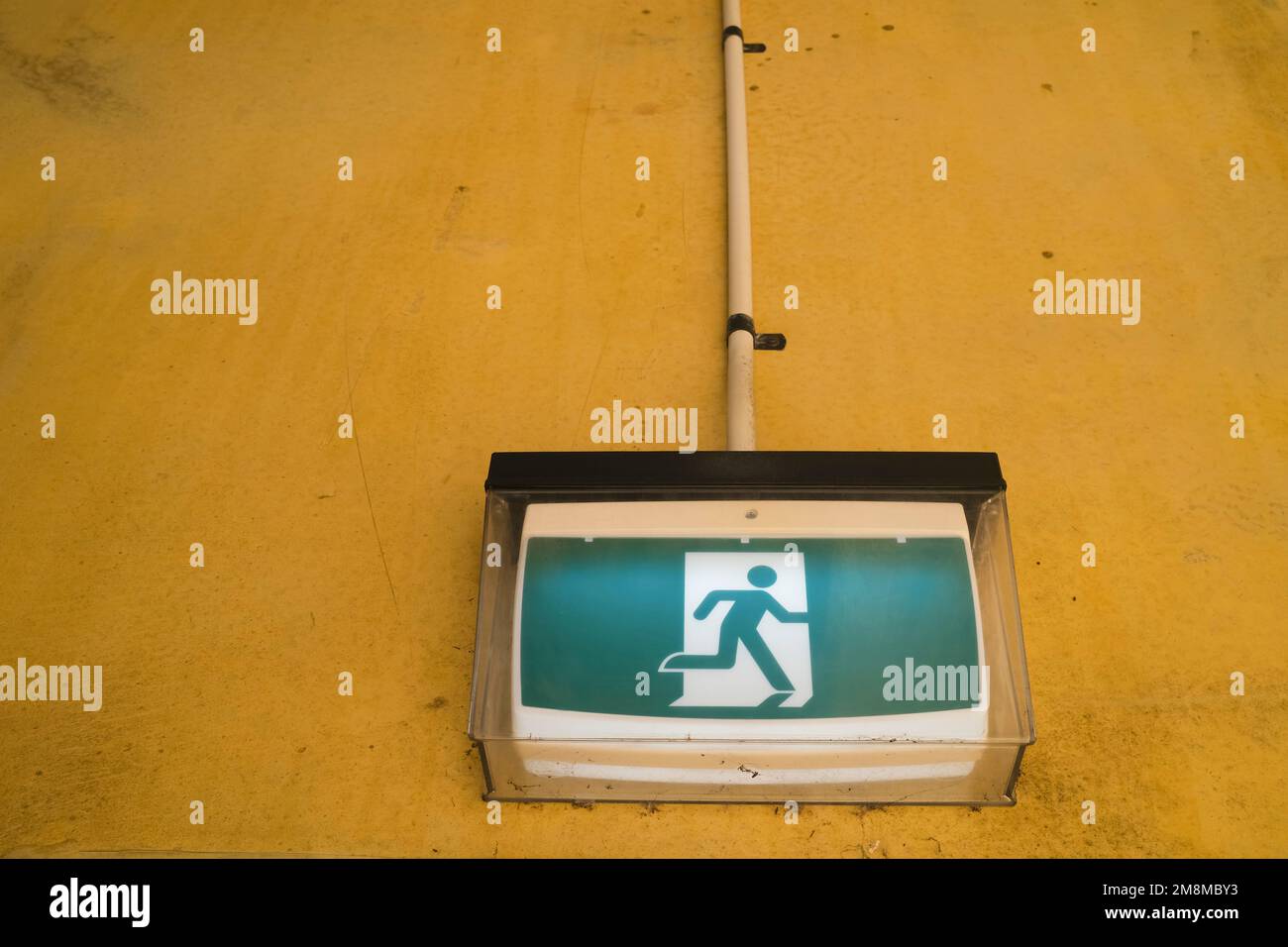 Running Man Emergency Exit sign on dirty wall Stock Photo