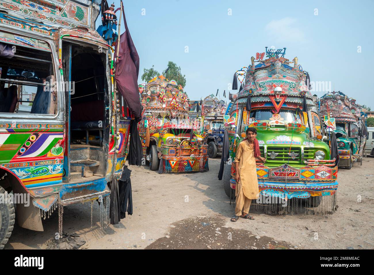 Bus driver in front of his colorfully painted bus, Peshawar, Pakistan Stock Photo