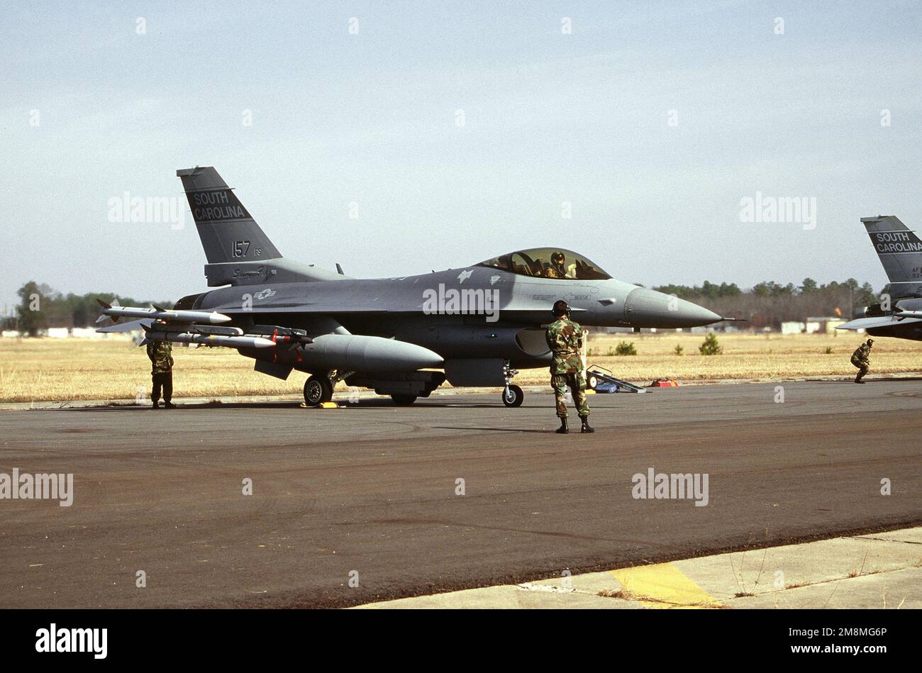 The maintenance crew and the pilot in the cockpit of an F-16C Falcon from the 169th Fighter Wing complete their preflight inspections. They are preparing for a 15+ hour flight to Qatar to participate with active duty units in the Air Expeditionary Force (AEF) deployment. The F-16 is armed with AIM-120 AMRAAM missiles. Base: Mcentire Ang Station State: South Carolina (SC) Country: United States Of America (USA) Stock Photo