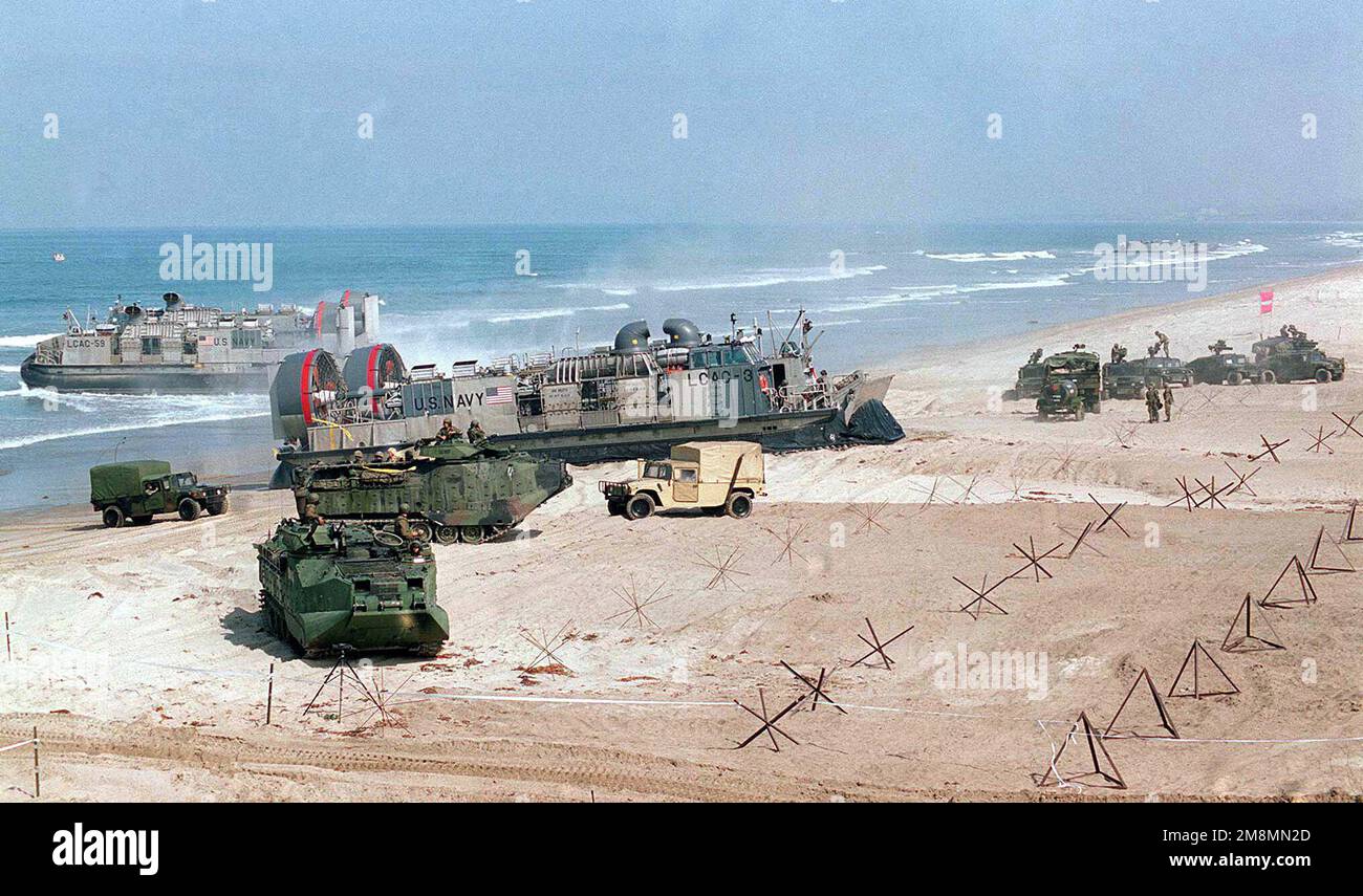 970628-M-9816M-030. [Complete] Scene Caption: Landing Craft, Air Cushioned (LCAC) unload a third wave of activity on Red Beach during the amphibious assault as part of Exercise KERNEL BLITZ 97 at Camp Pendleton, California. In foreground an Amphibious Assault Vehicle (AAV-7A1) starts to leave the beach while M998 High-Mobility Medium Wheeled Vehicles (HMMWV) are staged (right background). KERNEL BLITZ is a bi-annual Commander-in-CHIEF Pacific (CINCPAC) fleet training exercise (FLEETEX) focused on operational/tactical training of Commander, Third Fleet (C3F)/ I Marine Expeditionary Forces (MEF) Stock Photo