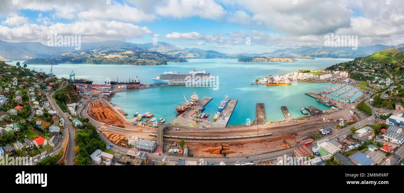 Scenic aerial panorama of Diamond harbour in Lyttleton port town of New zealand with busy cargo terminal and passenger cruise ship at wharf. Stock Photo