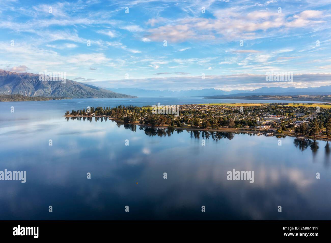 Calm reflection of Te Anau town on waterfront of Te Anau lake in Milford Sound Fiordland of New Zealand. Stock Photo