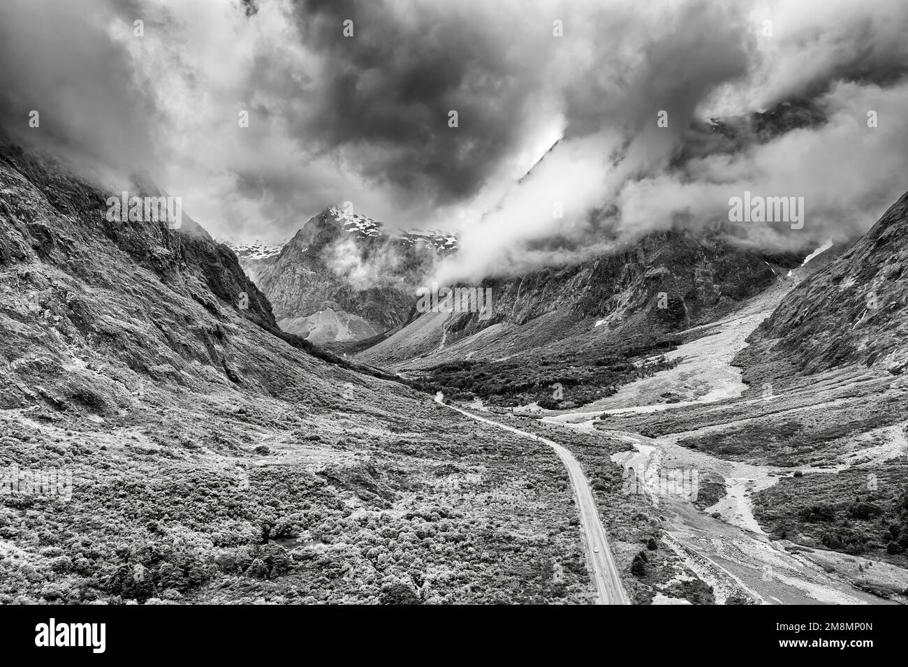 Dramatic black-white view ofonkey creek valley highway to Milford Sound fiord in New Zealand - scenic mountain landscape. Stock Photo