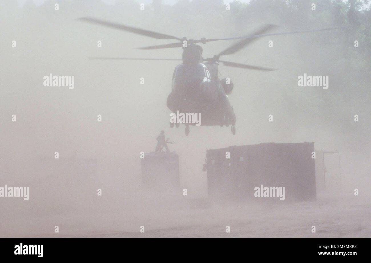 An Army National Guard CH-47 Chinook helicopter from Detachment 1, Company F, 106th Aviation Davenport, Iowa, whips up a sand storm as the crew prepares to sling load a conex box, filled with equipment, for redeployment from the Malali site back to Camp Stephenson. As part of the 106th, helicoopters and river boars provided the only access to this site in the rain forest more than 100 miles from Camp Stephenson during this first combined humanitarian and civic assistance exercise conducted between the United States and Guyana. Military personnel from the Air Force, Air Force Reserve and Nation Stock Photo