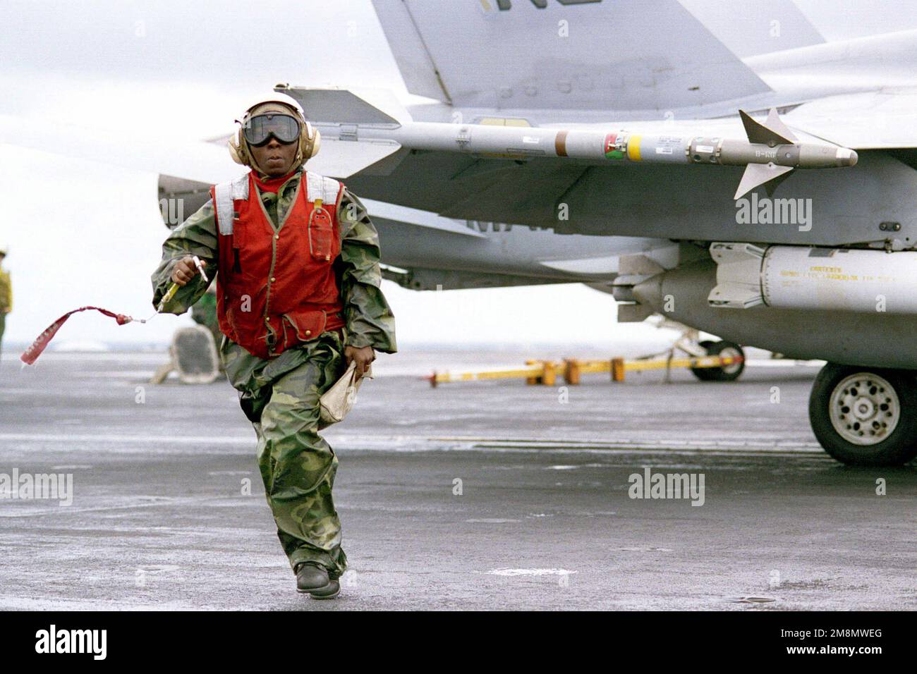 971112-N-3969M-317US Navy Aviation Ordnanceman Demica Stuard, Fighter Attack Squadron 147 (VFA-147) clears the launch area after arming an AIM-9 Sidewinder close range air-to-air missile on an F/A-18C Hornet during flight operations. The nuclear powered aircraft carrier USS NIMITZ (CVN 68) is currently operating in the Persian Gulf to support UN sanctions against Iraq, by enforcing the No-Fly Zone. Operation SOUTHERN WATCH, 12 November 1997. 971112-N-3969M-317 US Navy Aviation Ordnanceman Demica Stuard, Fighter Attack Squadron 147 (VFA-147) clears the launch area after arming an AIM-9 Sidewind Stock Photo