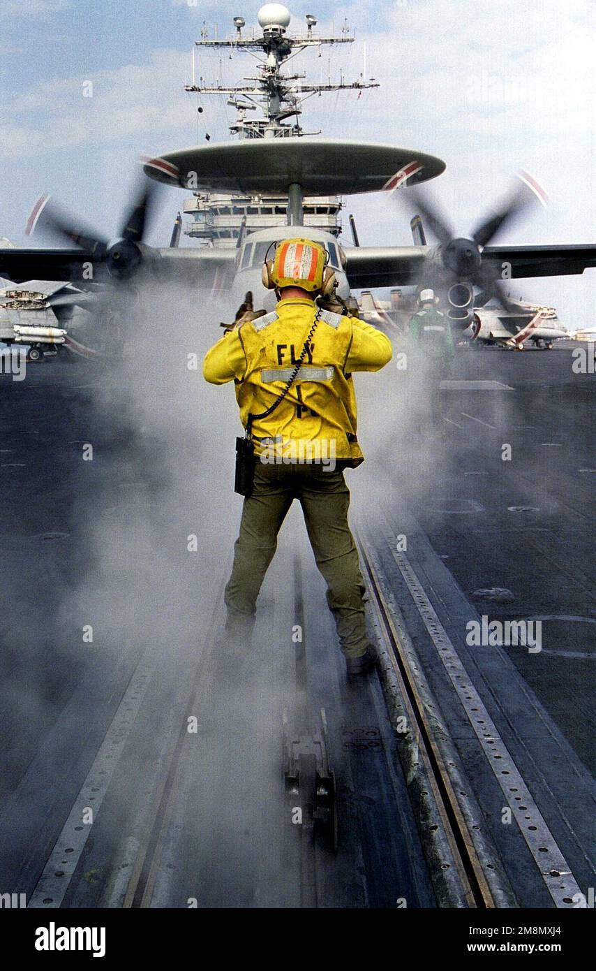 Aviation Boatswains Mate 3rd Class Kevin P. Spurrell directs an E2C Hawkeye onto one of four