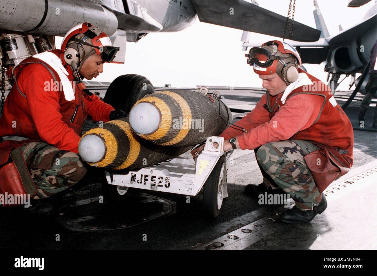 Aviation Ordnanceman 2nd Class Alvin Toney (right) and Aviation Ordnanceman 3rd Class Steve Chilton load a MK-83 1000-pound bomb onto an F/A-18C Hornet aboard the aircraft carrier USS GEORGE WASHINGTON (CVN 73). George Washington deployed to the Persian Gulf in support of Operation Southern Watch. Subject Operation/Series: SOUTHERN WATCH Base: USS George Washington (CVN 73) Country: At Sea Stock Photo