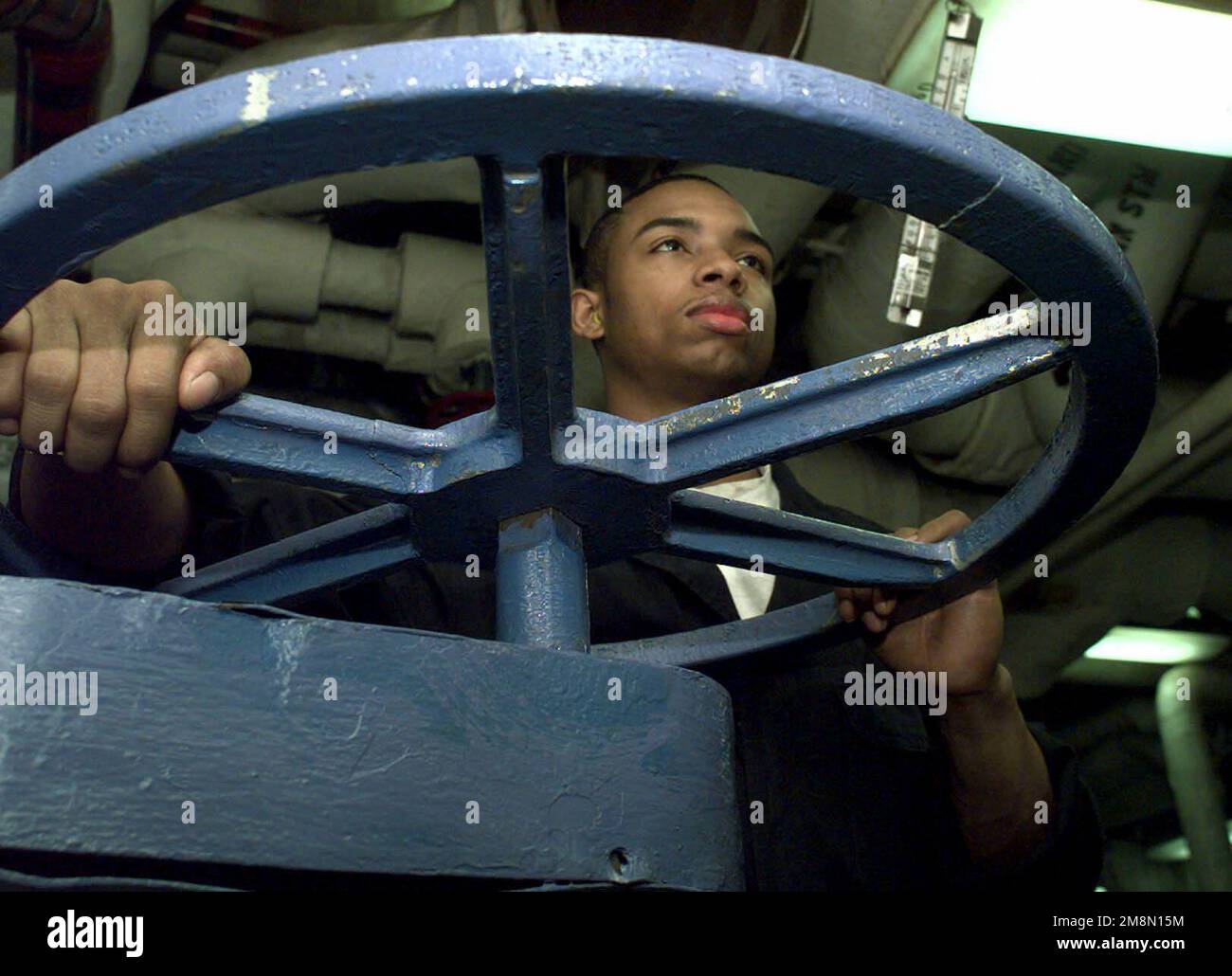 US Navy Fireman John Jones opens a valve that controls the water levels