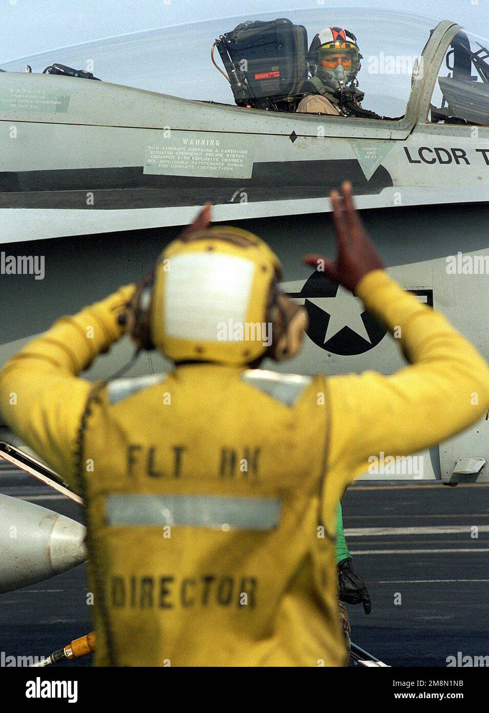 Right side profile, past the Flight Deck Director, at the cockpit section on an F/A-18 Hornet pilot prepares to lauch from the flight deck of USS GEORGE WASHINGTON (CVN-73) while underway in the Arabian Sea. The ship is in the gulf as part of the Southwest Asia (SWA) build-up of forces in reaction to Iraq's refusal of U.N. sponsored weapon's inspections. Country: Unknown Stock Photo