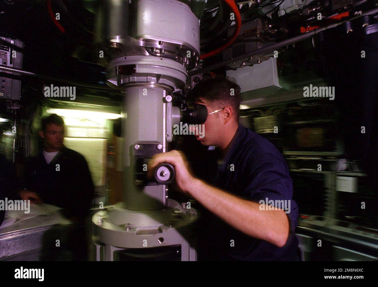 As the Los Angeles class attack submarine USS PASADENA (SSN 752)prepares to surface during RIMPAC '98, MM2 (SS) Tommy Wilkins peers through the periscope to ensure no surface contacts exist that would interfere with the submarine's surfacing. Subject Operation/Series: RIMPAC '98 Country: Pacific Ocean (POC) Stock Photo