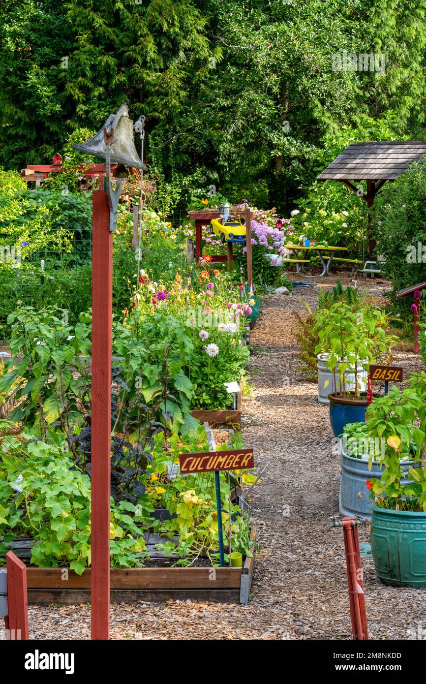 Bellevue, Washington, USA.   Entrance to Bellevue Demonstration Garden, including a bell that can be rung.  In the distance is a 'Tin Man' driving a t Stock Photo