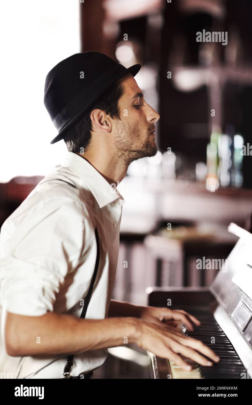 Music is a great form of artistic expression. A handsome young man playing the piano in a club. Stock Photo
