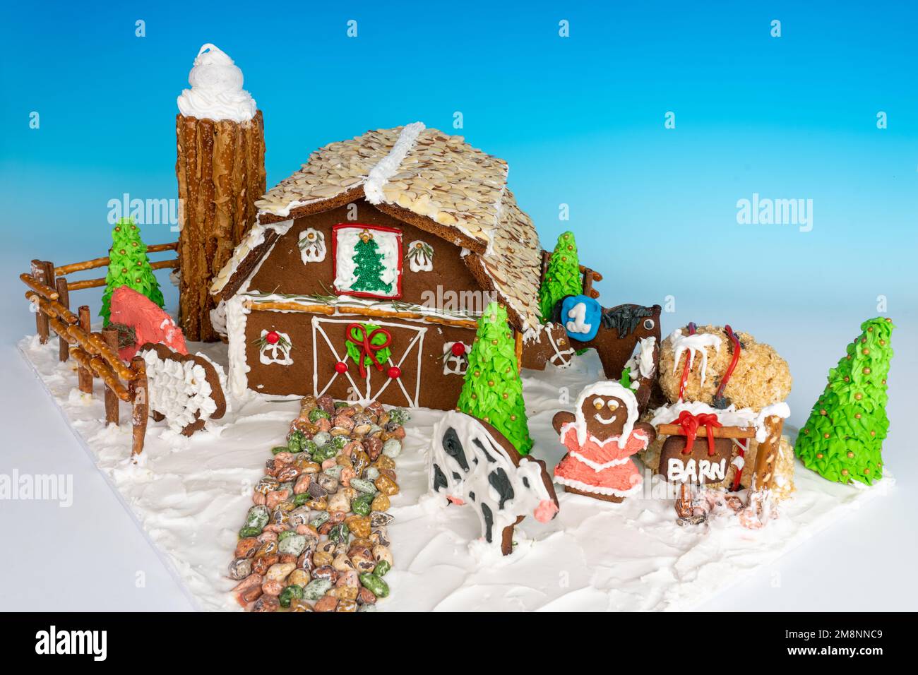 Front side of a homemade gingerbread barn with silo, farm animals, girl, boy, hay bales and trees,surrounded by a fence, all made of totally edible ma Stock Photo