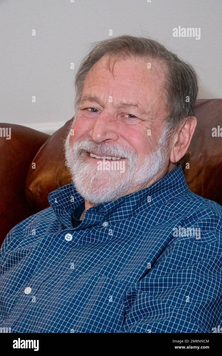 Portrait of a happy 75 year old bearded man sitting in a leather chair. (MR) Stock Photo