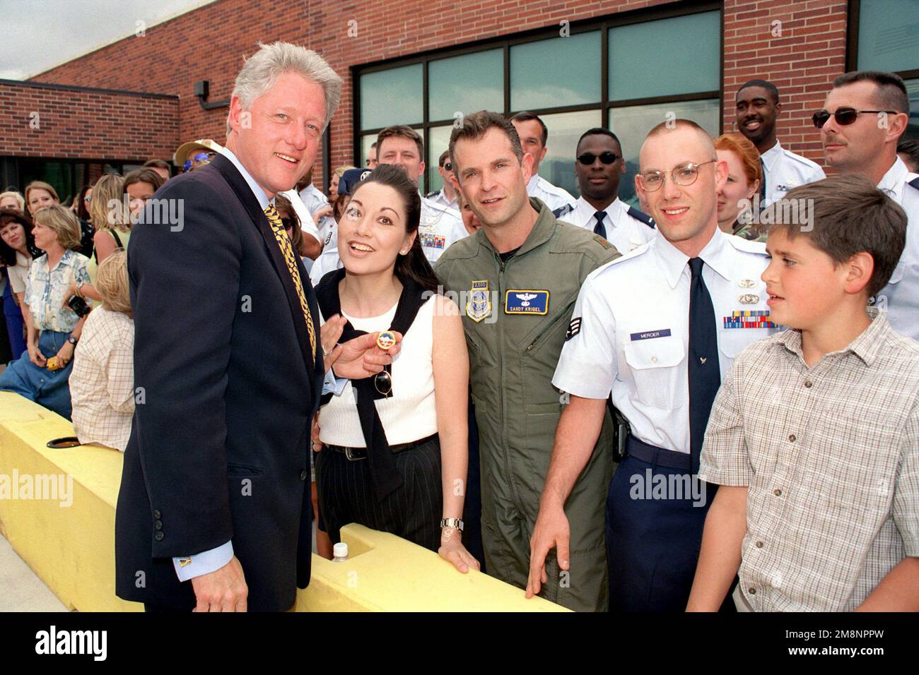 President William Jefferson Clinton holds a coin presented to him by the 84th Airlift Flight Commander, Major Sandy J. Krigel (In flight suit) and his wife Lili (Next to the Pres.). This event to place upon the President's departure from Peterson Air Force Base, Colorado, on June 2nd, 1999. Base: Peterson Air Force Base State: Colorado (CO) Country: United States Of America (USA) Stock Photo