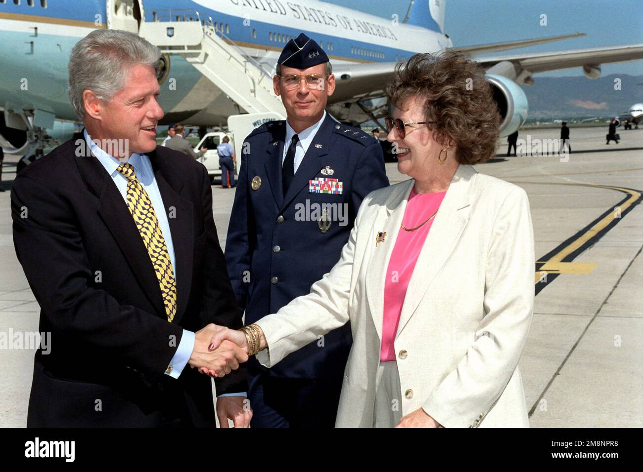 President William Jefferson Clinton shakes hands with Mrs. Becky Lord, wife of US Air Force Lieutenant General Lance Lord (Center), Vice Commander, Air Force Space Command, Peterson Air Force Base, Colorado. This event took place on the Peterson AFB flight on June 2nd, 1999. Air Force One is parked on the flight line in the background. Base: Peterson Air Force Base State: Colorado (CO) Country: United States Of America (USA) Stock Photo