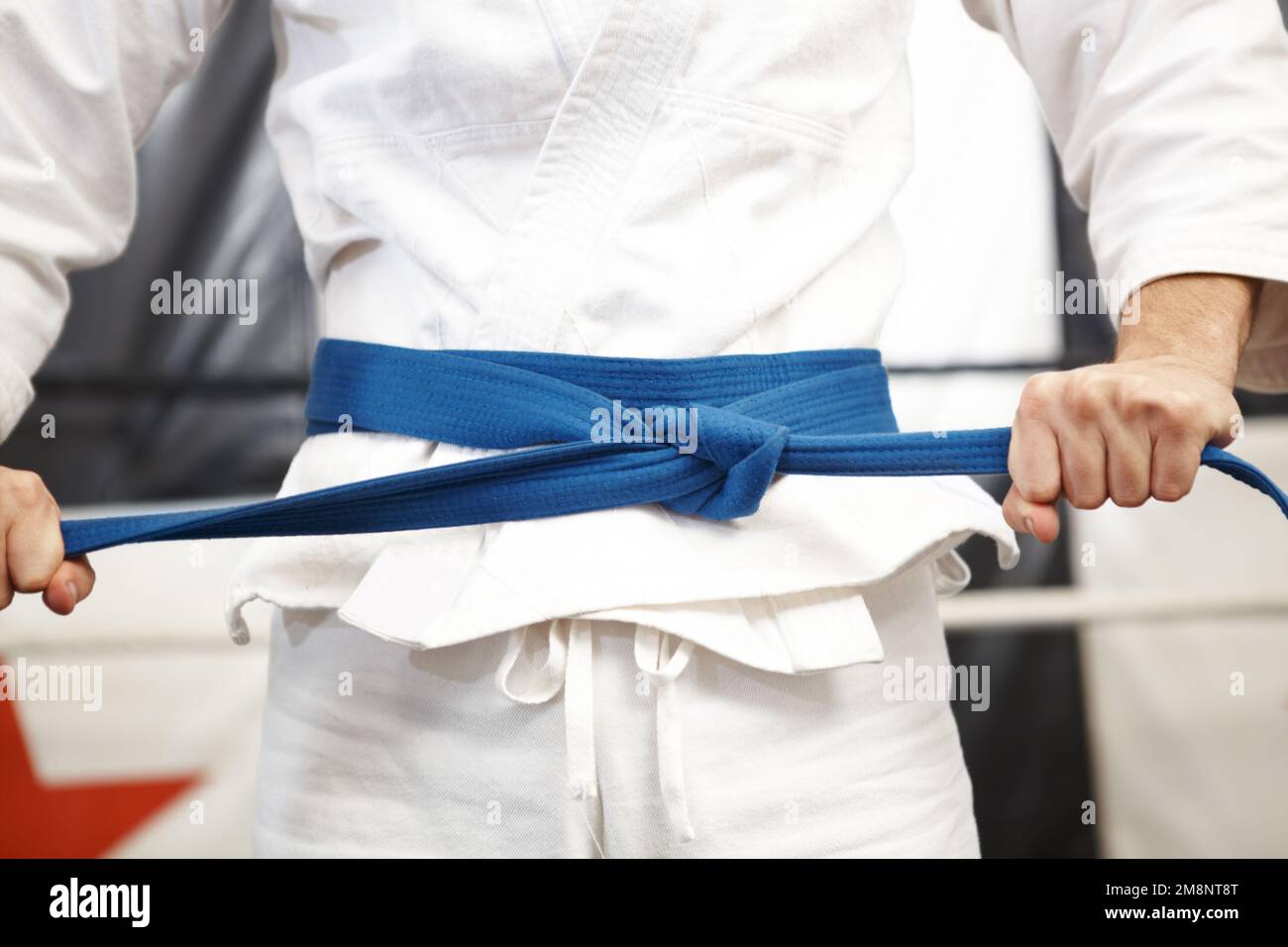 Tight for a fight. martial artist putting on his gi and tying his belt