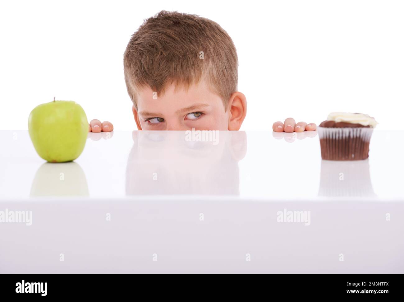 Apple, cake and choice with a boy deciding between sweets or health in studio on a white background. Food, fruit and decision with a male child Stock Photo