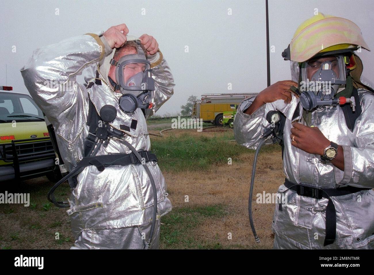 Tecnical Sergfeant Alfonso Iceman (rigth) and STAFF Sergeant John Rhoades (left), 169th Fighter Wing, South Carolina Air National, adjust protective clothing in preparation for fire rescue training. This training is held at Logan Airport Boston, Massachusetts, 25 July 1999. Base: Logan Airport, Boston State: Massachusetts (MA) Country: United States Of America (USA) Stock Photo