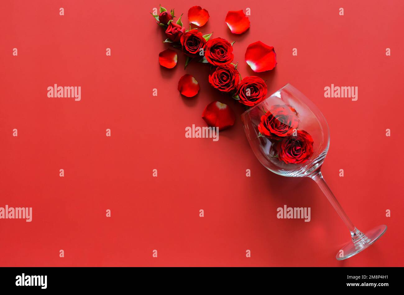 Red roses with empty red wine glass put on red background for ...