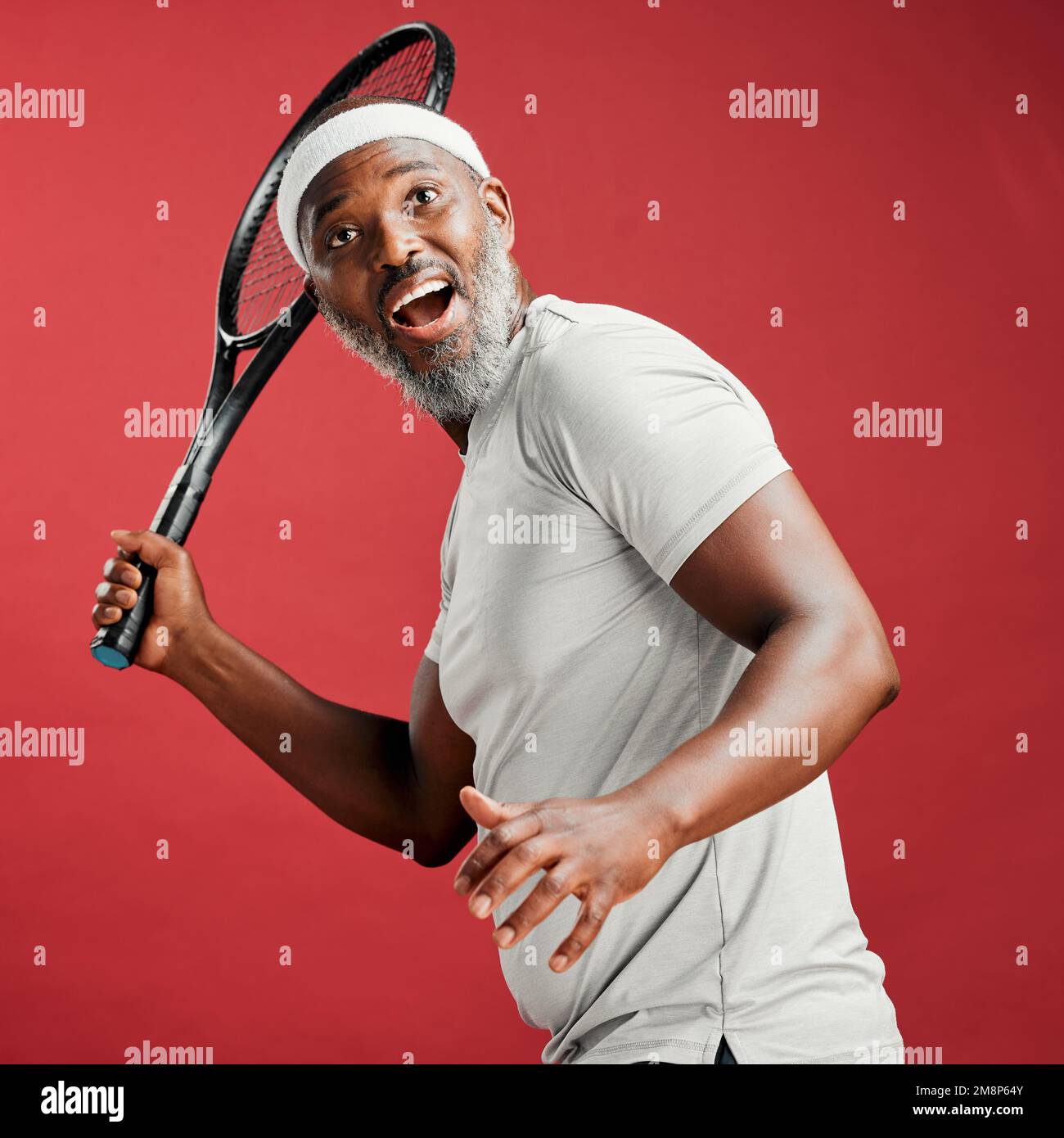 Man Using Tennis Racket One happy mature african american man standing against a red background ...