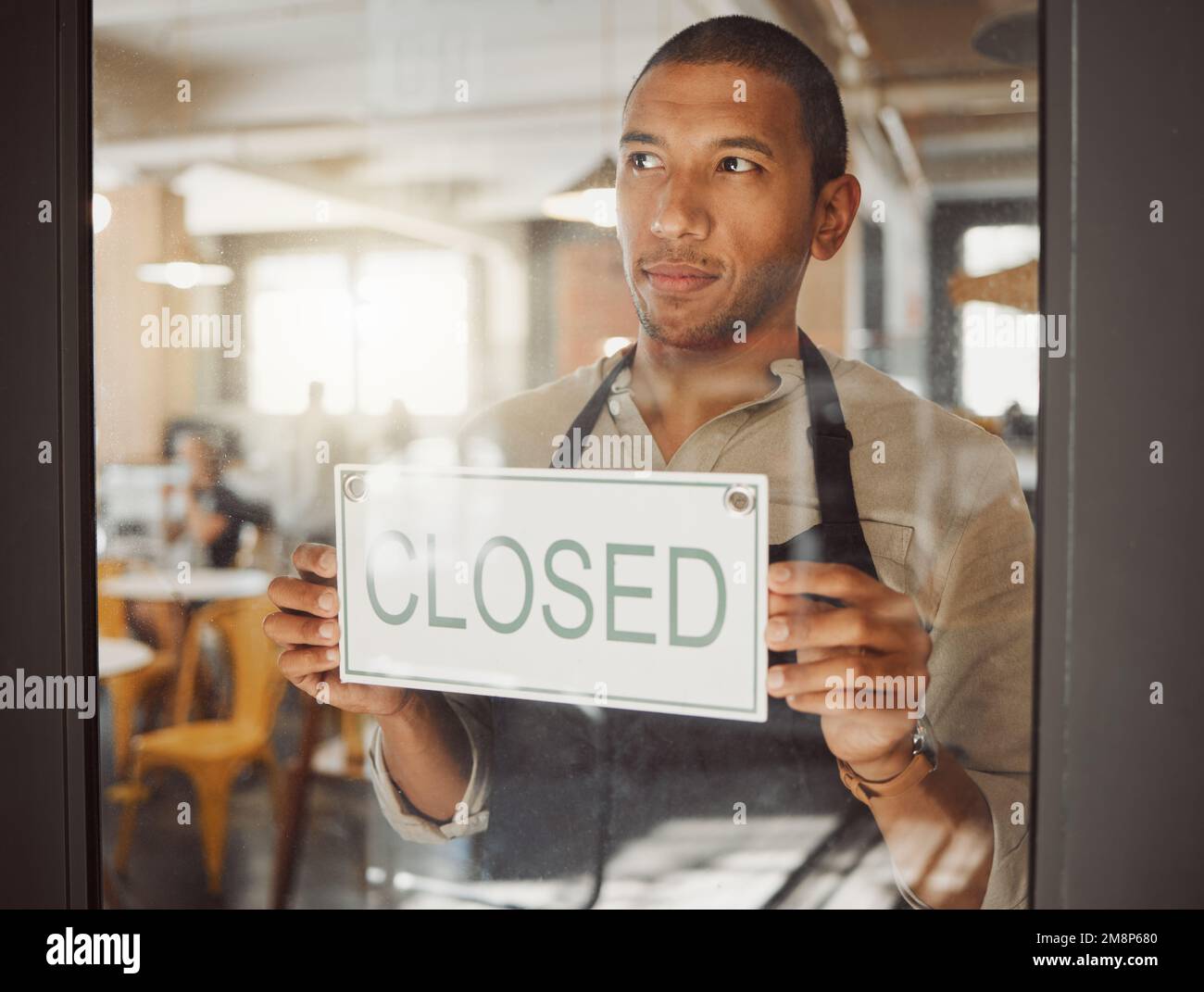 Businessman hanging a closed sign in his shop door. Bistro boss closing his restaurant. Shop assistant closing the store alone. Business owner Stock Photo