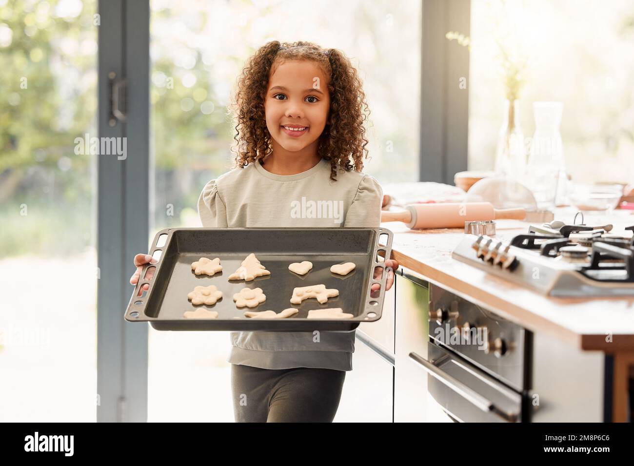 One cute little mixed race girl looking happy and proud while baking ...