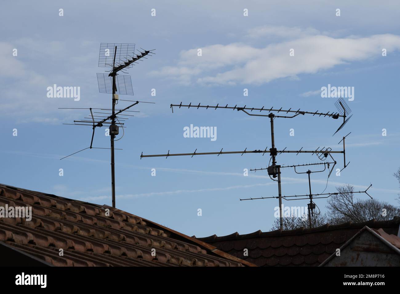 The rooftops made of red tiles with analog antennas attached to the