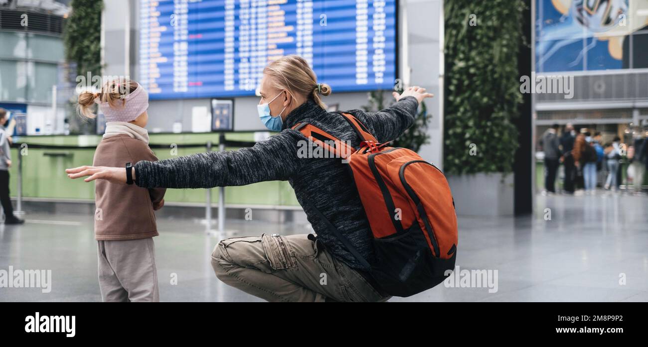 Man and girl watching timetable information at the airport, passengers waiting for a plane. Family travel by airplane. Flight delay Stock Photo