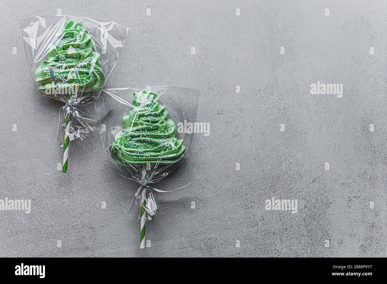 Two green decorative christmas-tree-shaped meringue lollipops on stone table. Festive desserts. Holidays. Horizontal shot. High quality photo Stock Photo