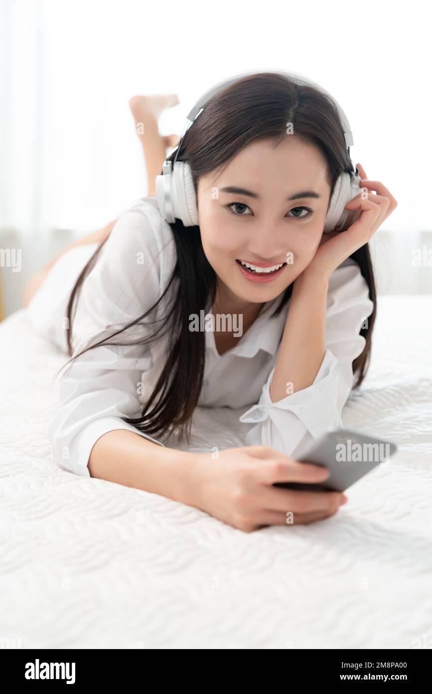 A young woman lying on the bed to listen to music Stock Photo - Alamy