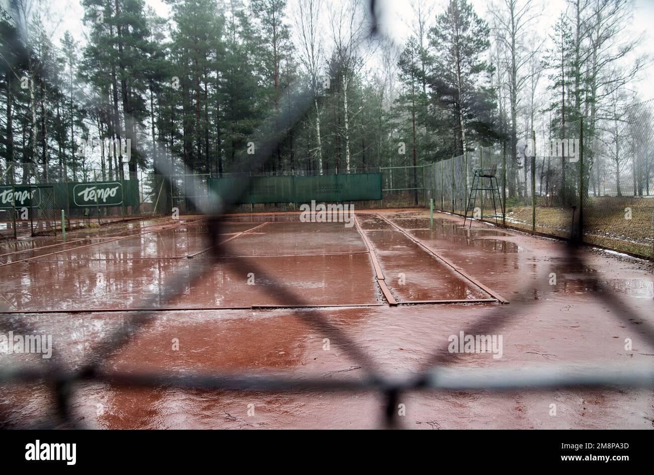 sand tennis court seen through fence, red ground ,winter Stock Photo