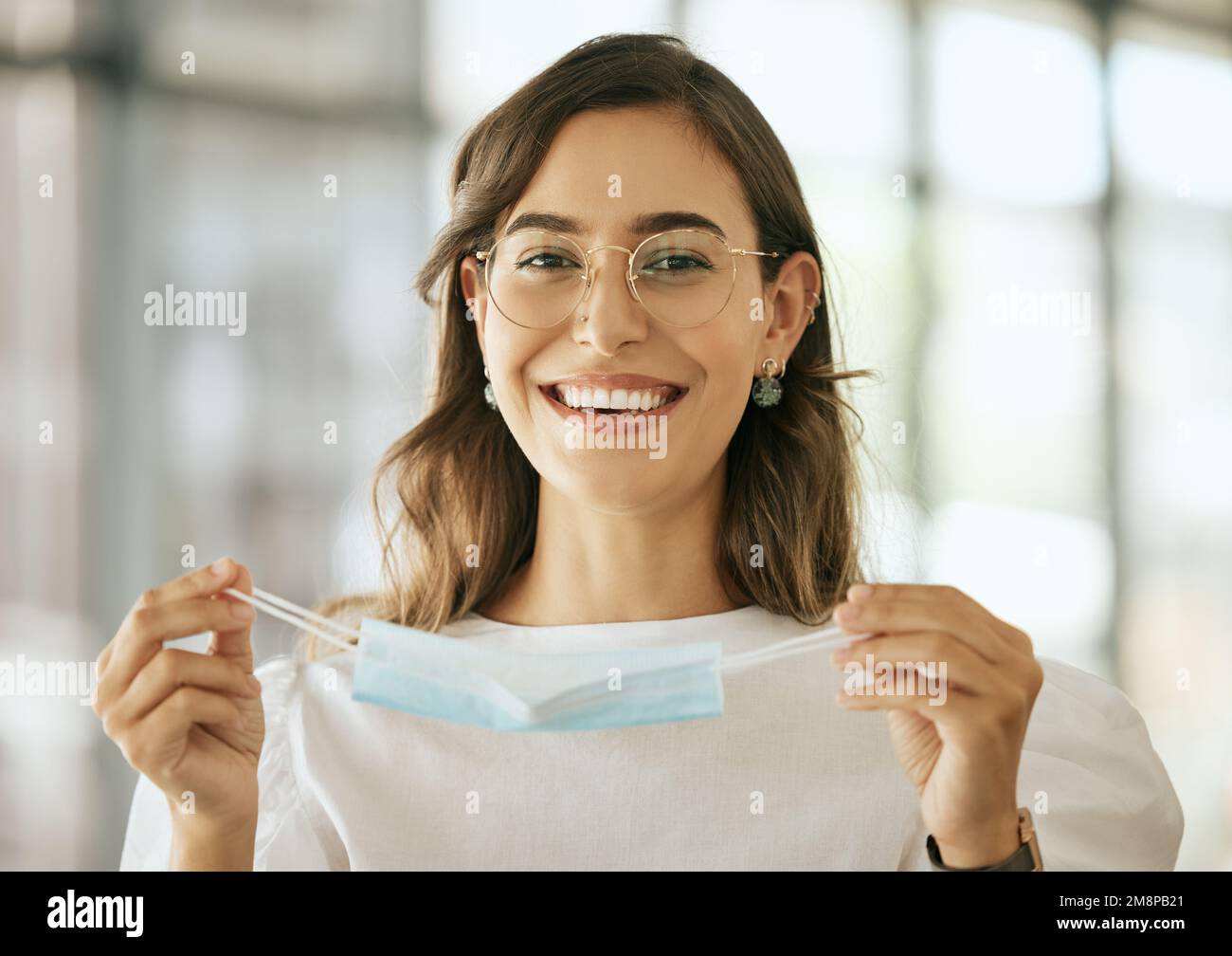 Business woman putting on protective face mask in the office for safety ...