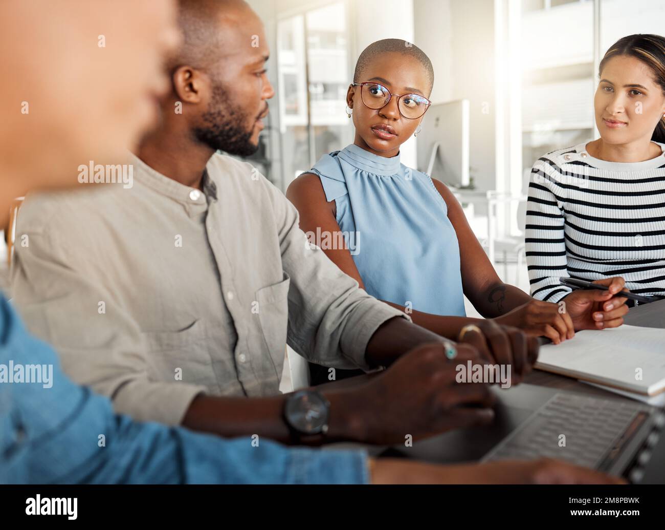 Group of diverse businesspeople having a meeting in an office at work. Business professionals talking while using a laptop together in an office Stock Photo