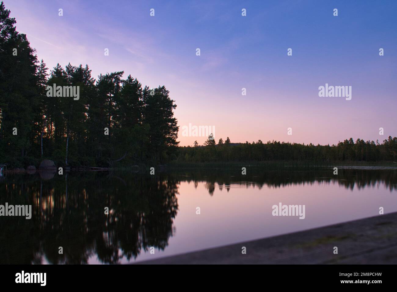 A silhouette of trees by the lake during the sunset Stock Photo - Alamy