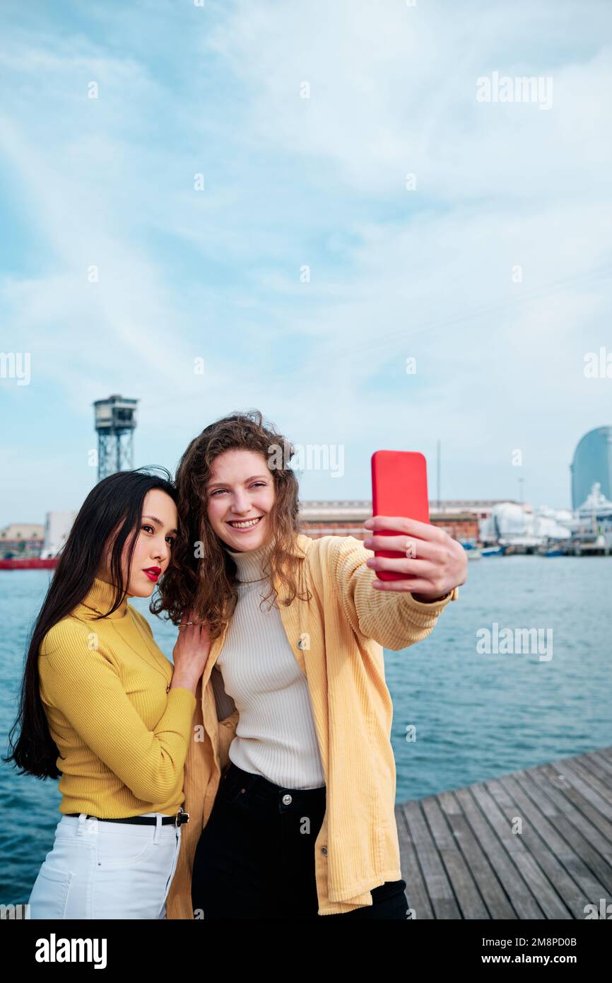 Two Women Taking Selfies With A Mobile Phone Outdoors On The Sea