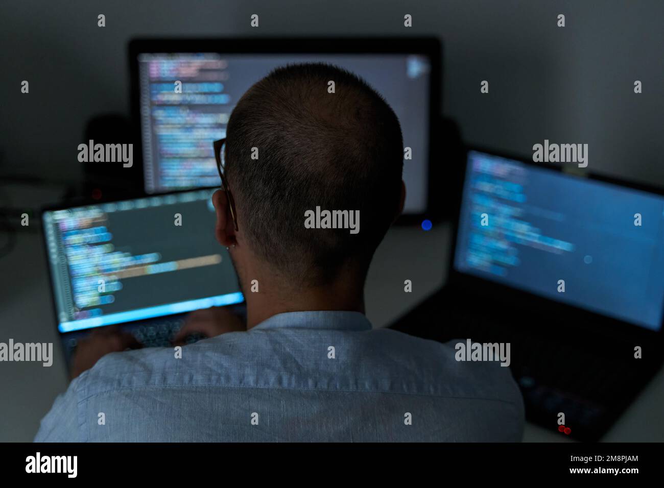 Heavy workload concept. Male coding with three screens at office Stock ...