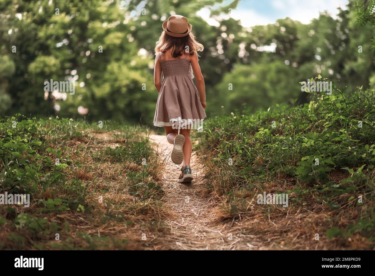 Summer school holidays. Back view of little girl in a straw hat and ...