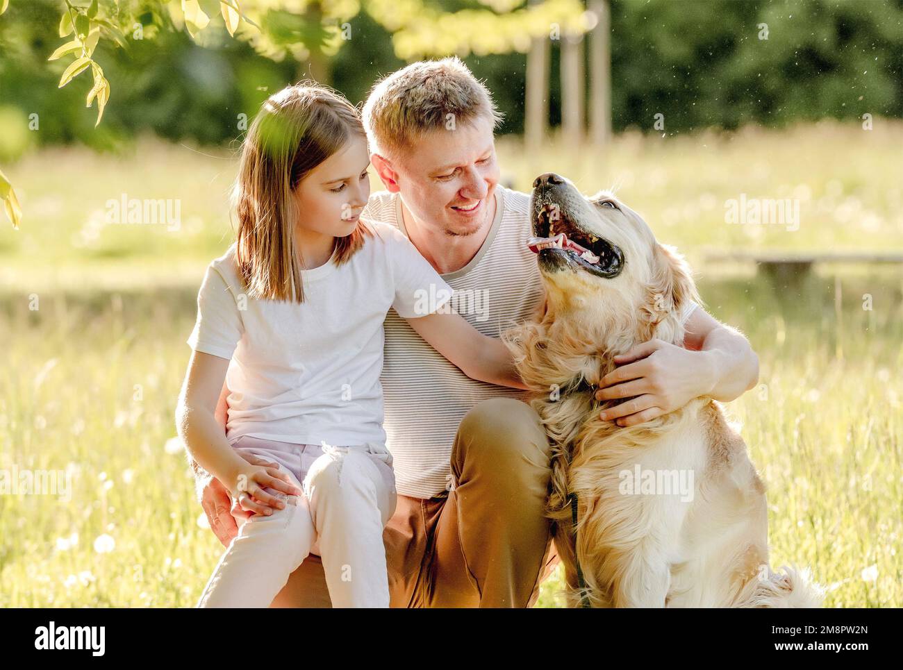 Dad and his daugter play with dog Stock Photo