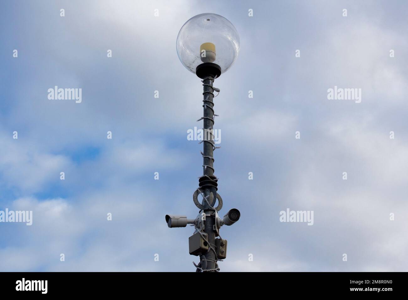 Two surveillance cameras on the metal street light lamp post outdoor on