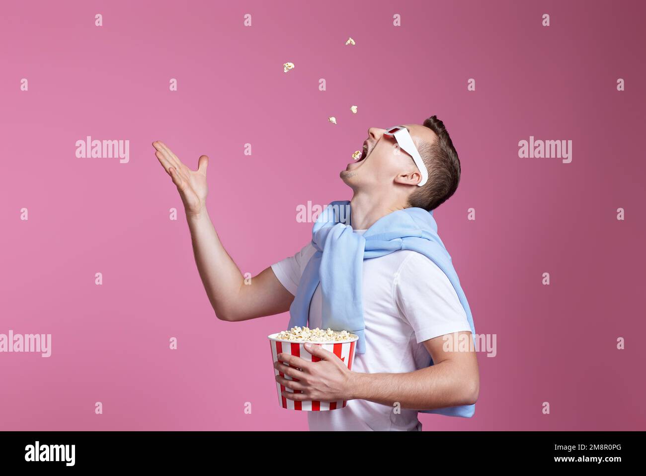 handsome man in 3d glasses throwing up and eating popcorn Stock Photo