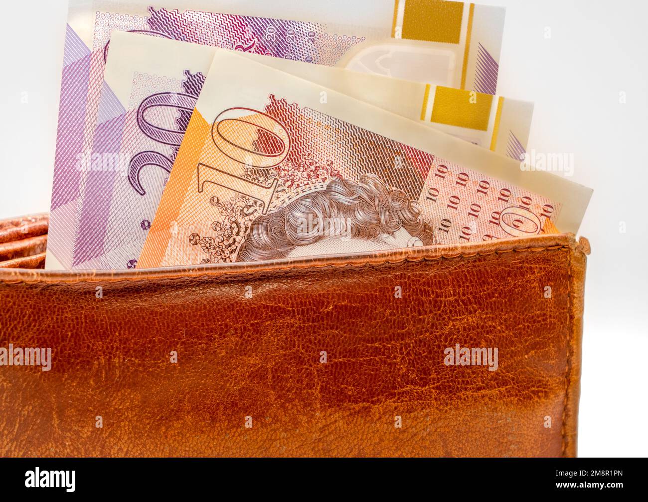 close-up of a pile of ten and twenty pound sterling notes with a brown leather wallet Stock Photo