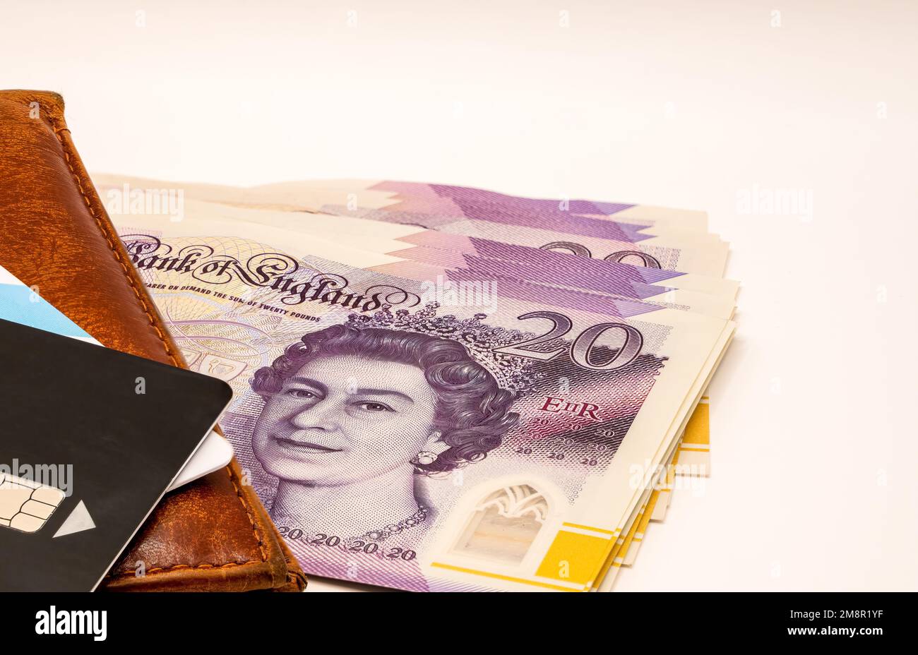 close-up of a pile of ten and twenty pound sterling notes with a brown leather wallet and black bank card Stock Photo