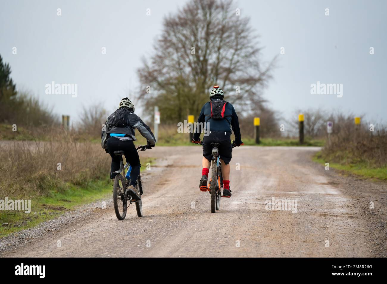 a pair of casual cyclists riding along across a country mud track Stock Photo