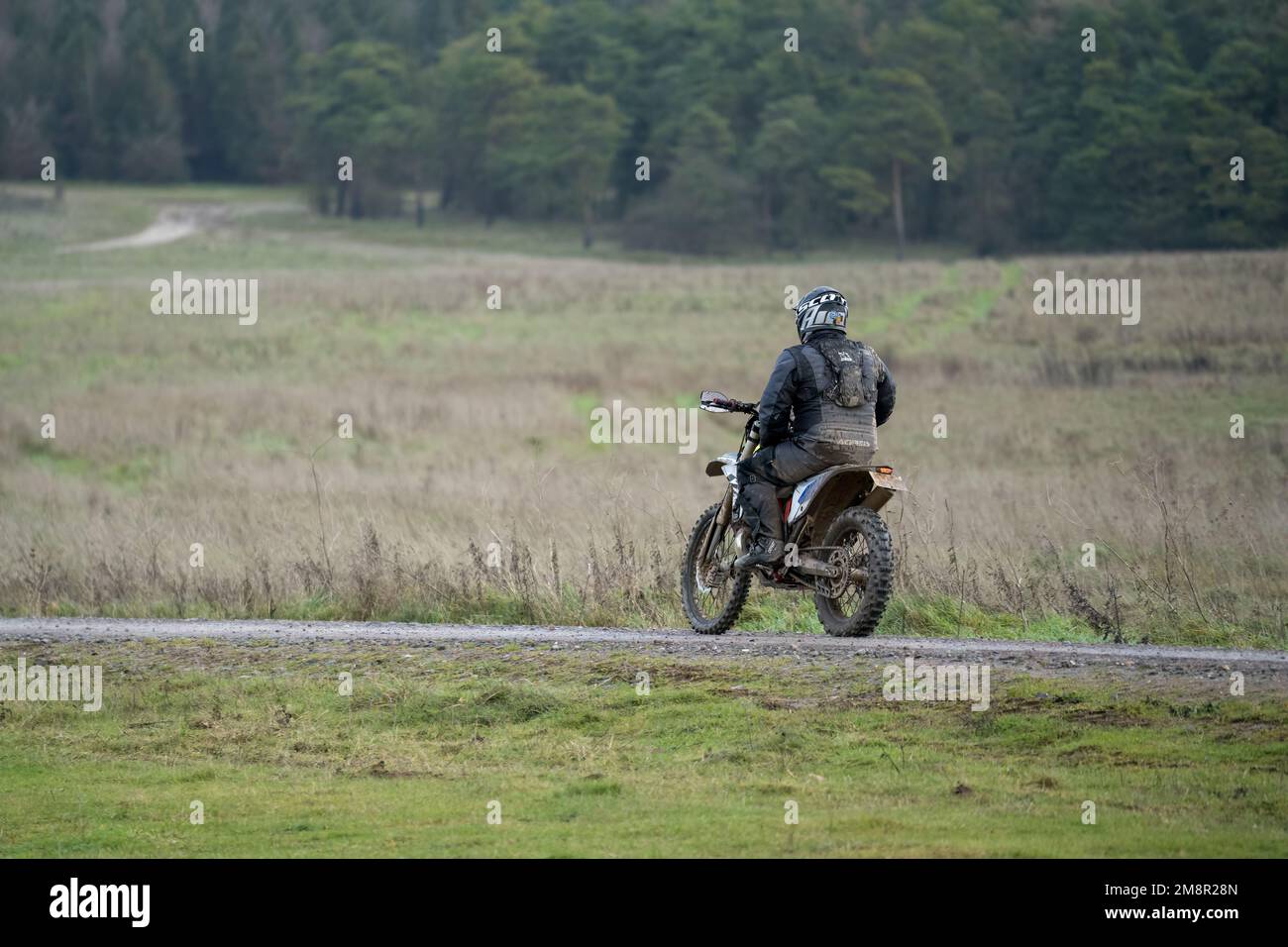 a motor cyclist (biker) riding his off-road motorbike along a stone track on Salisbury Plain, Wiltshire Stock Photo